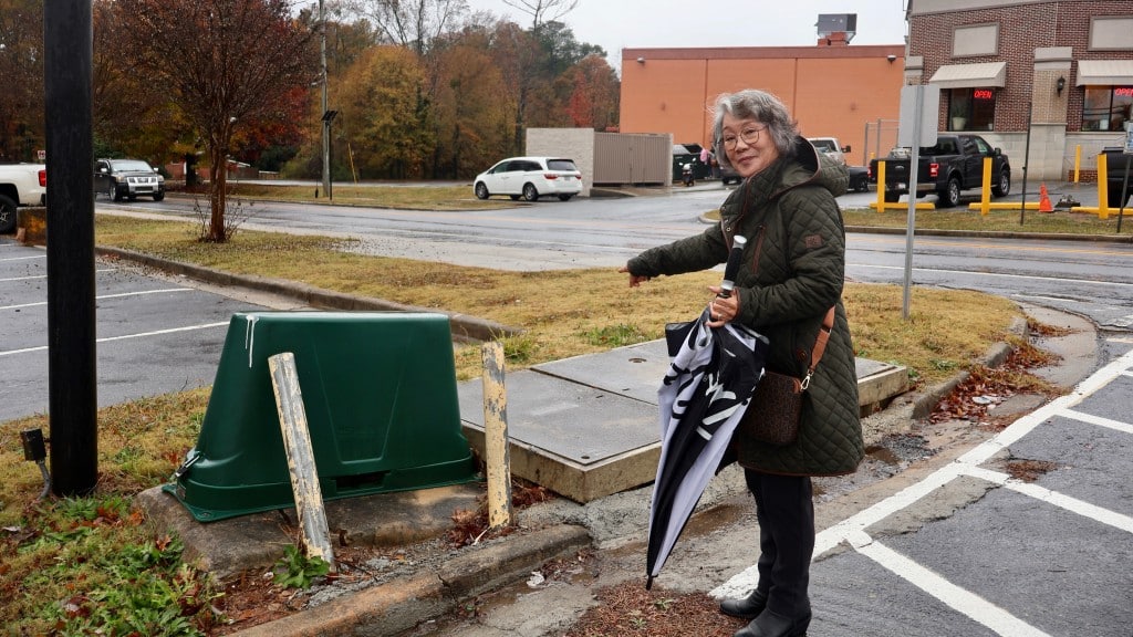 Kay Park points out a water meter on the Treasure Village property she manages on Buford Highway. (Zoey Laird)