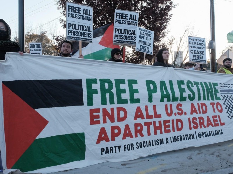 Protesters hold a banner showing support for Palestine at the International Day of Solidarity protest for Palestine in Atlanta. The banner says, "Free Palestine. End all U.S. aid to Apartheid Israel"