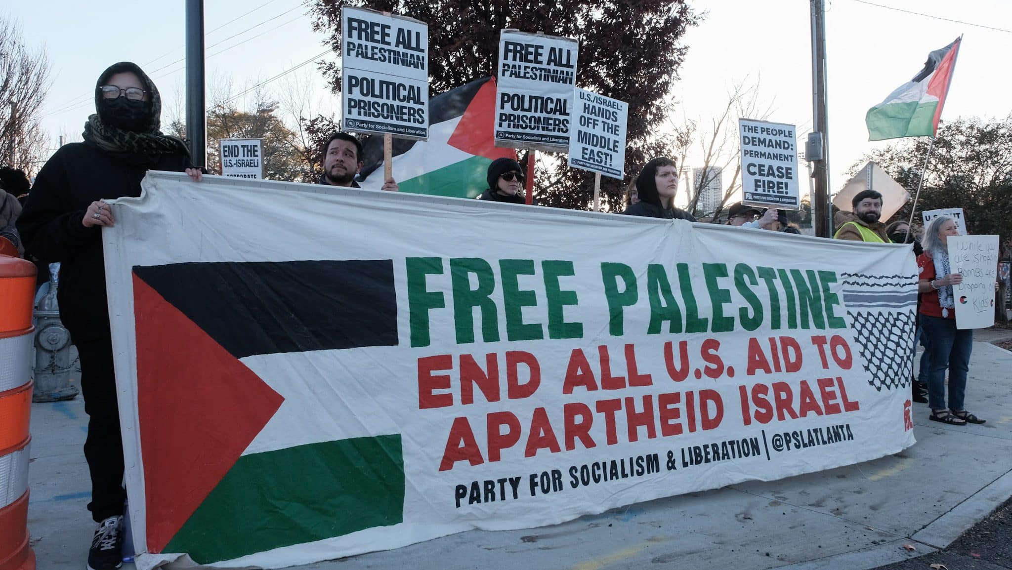 Protesters hold a banner showing support for Palestine at the International Day of Solidarity protest for Palestine in Atlanta. The banner says, "Free Palestine. End all U.S. aid to Apartheid Israel"