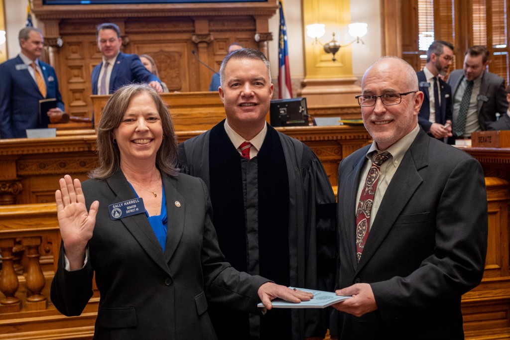 Senator Sally Harrell is sworn in on a copy of the Georgia Constitution held by her husband in the Georgia Senate chambers.