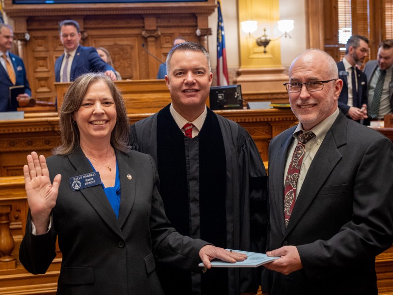 Senator Sally Harrell is sworn in on a copy of the Georgia Constitution held by her husband in the Georgia Senate chambers.