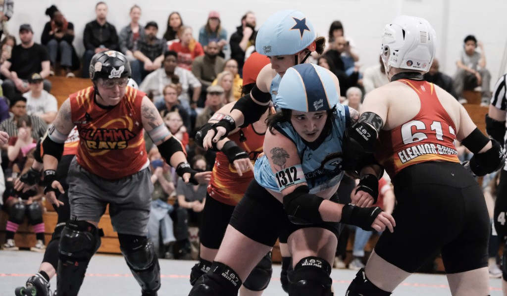A roller derby player blocks another roller derby player on the track.