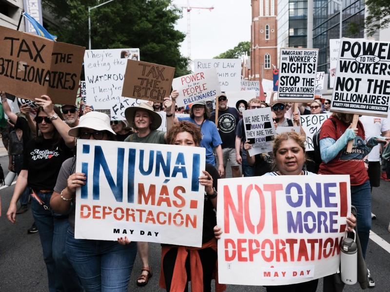 Marchers hold anti-deportation signs during the "Stop the Billionaire Agenda" march on International Workers Day in Downtown Atlanta.