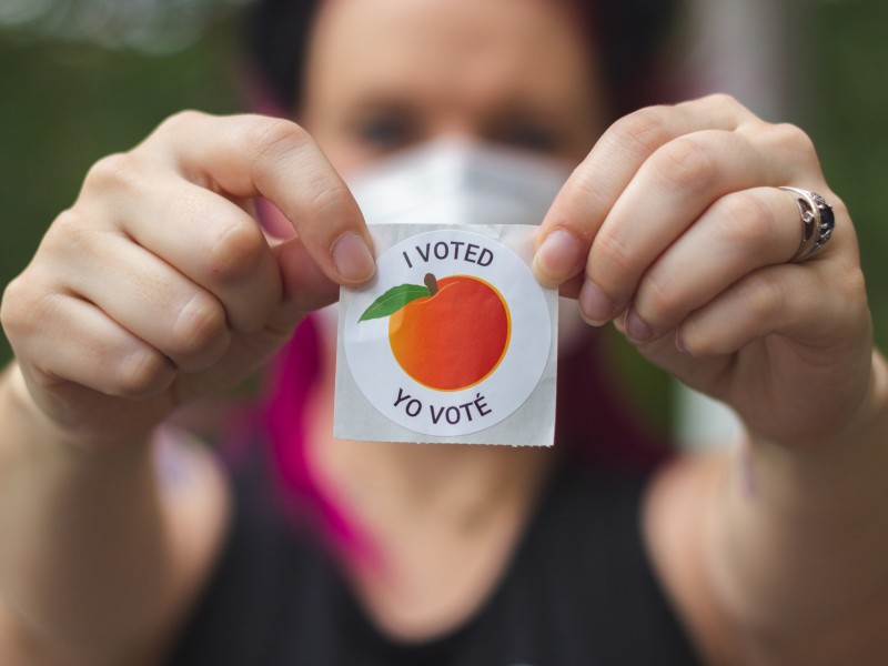 A voter in Lawrenceville, Georgia, holds up her "I Voted" sticker. On July 29, 2025, the Georgia Secretary of State's Office announced the Summer 2025 "No Contact" voter registration list.