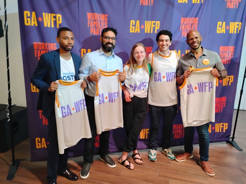 A group of five Atlanta municipal candidates standing together and holding jerseys that read "GA WFP"