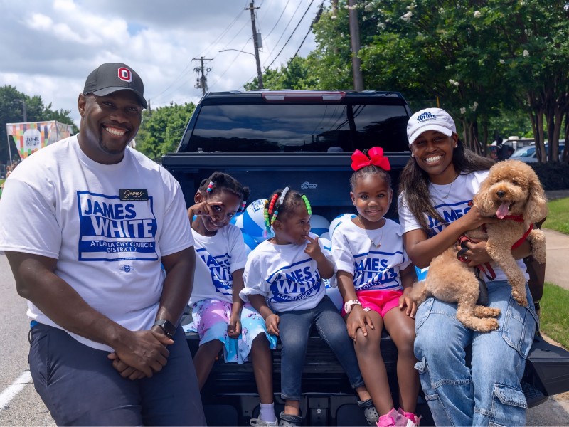 A man and a woman sit on a truck bed with three children between them.