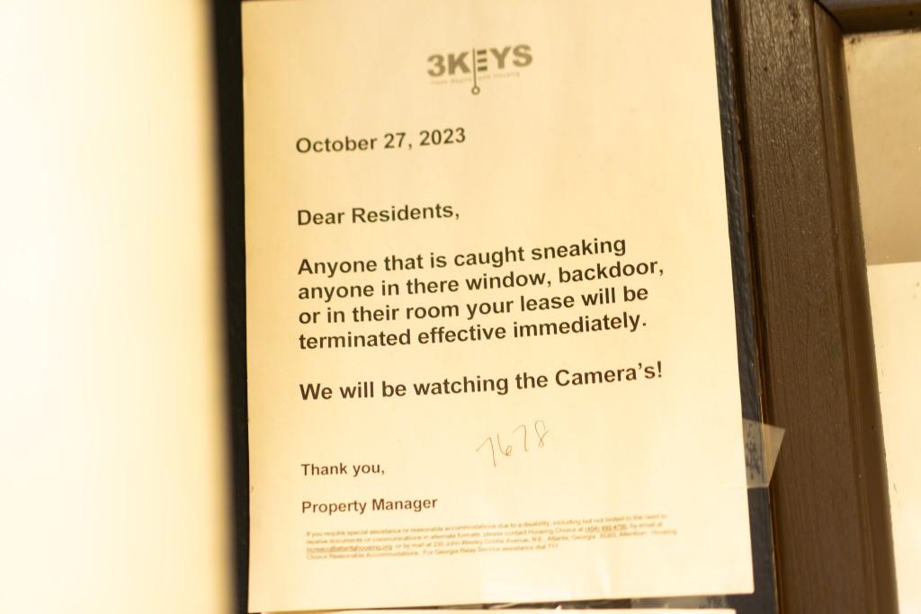 A sign with the 3KEYS logo that reads "Dear Residents, Anyone that is caught sneaking anyone in there (sic) window, backdoor, or in their room your lease will be terminated effective immediately. We will be watching the Camera's (sic)! Thank you, Property Manager"