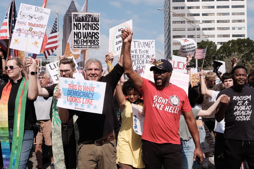 Two protestors at the No Kings 2 rally in Atlanta hold their hands