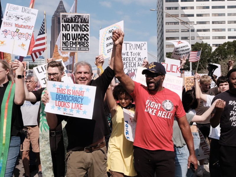 Two protestors at the No Kings 2 rally in Atlanta hold their hands