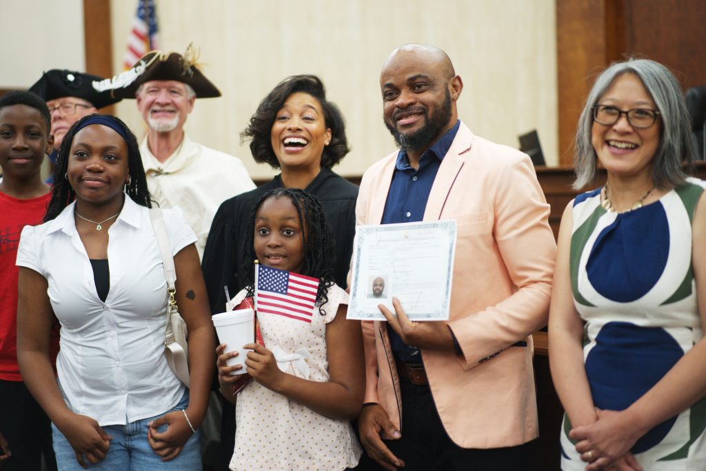 Danny Kabuya, from the Democratic Republic of the Congo, poses next to Judge Tiffany Johnson after his naturalization ceremony, while those seeking U.S. Citizenship from the Republic of Congo face delays. 