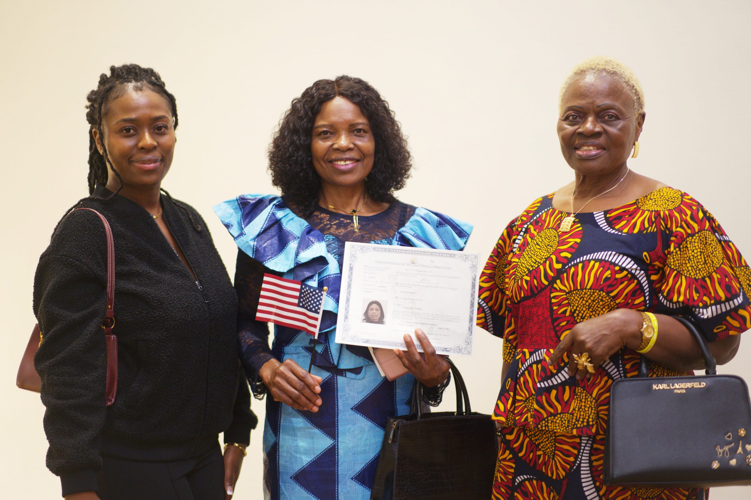 Angela Sirri Neba, from Cameroon, holds her naturalization certificate outside the courtroom, with one of her daughters and a friend, at Richard B. Russell Federal Building, on Friday, Apr. 17, 2026. Jesse Pratt López / ACPC